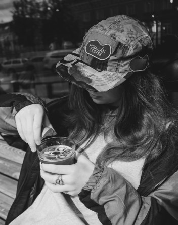 A woman in a Huracán cap drinking coffee