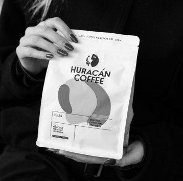 A hand holding a Huracán Coffee bag